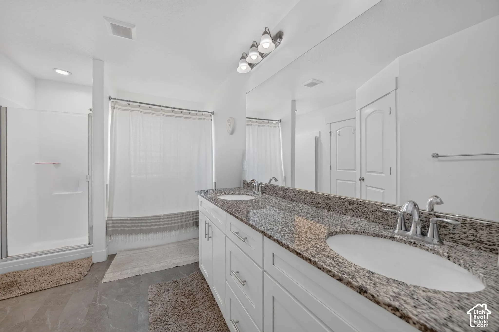 Dual vanity with stone-finish countertop and undermount sinks, chrome fixtures, and white cabinetry