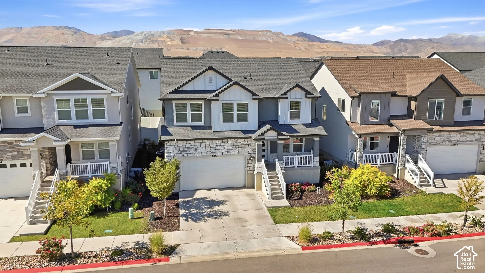 Stone facade with siding accents, attached two-car garage, covered porch entry, and mature landscaping