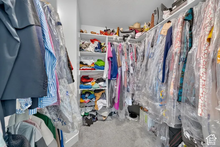 Additional contentThis image shows a walk-in closet in active use with clothing stored in plastic garment bags and folded items on shelves
