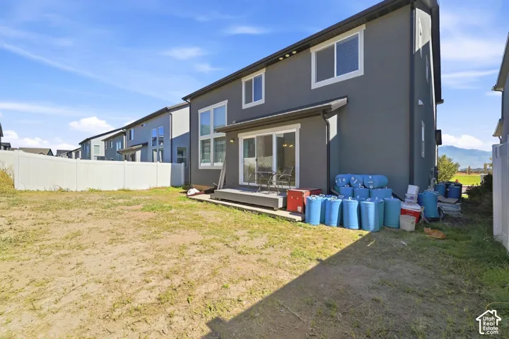 Rear exterior featuring a sliding glass door, elevated deck, and white vinyl fencing