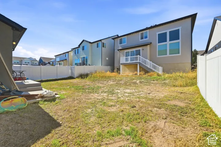 Expansive backyard with a level lawn area, white vinyl privacy fencing, and concrete patio