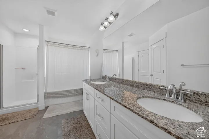Dual vanity with stone-finish countertop and undermount sinks, chrome fixtures, and white cabinetry