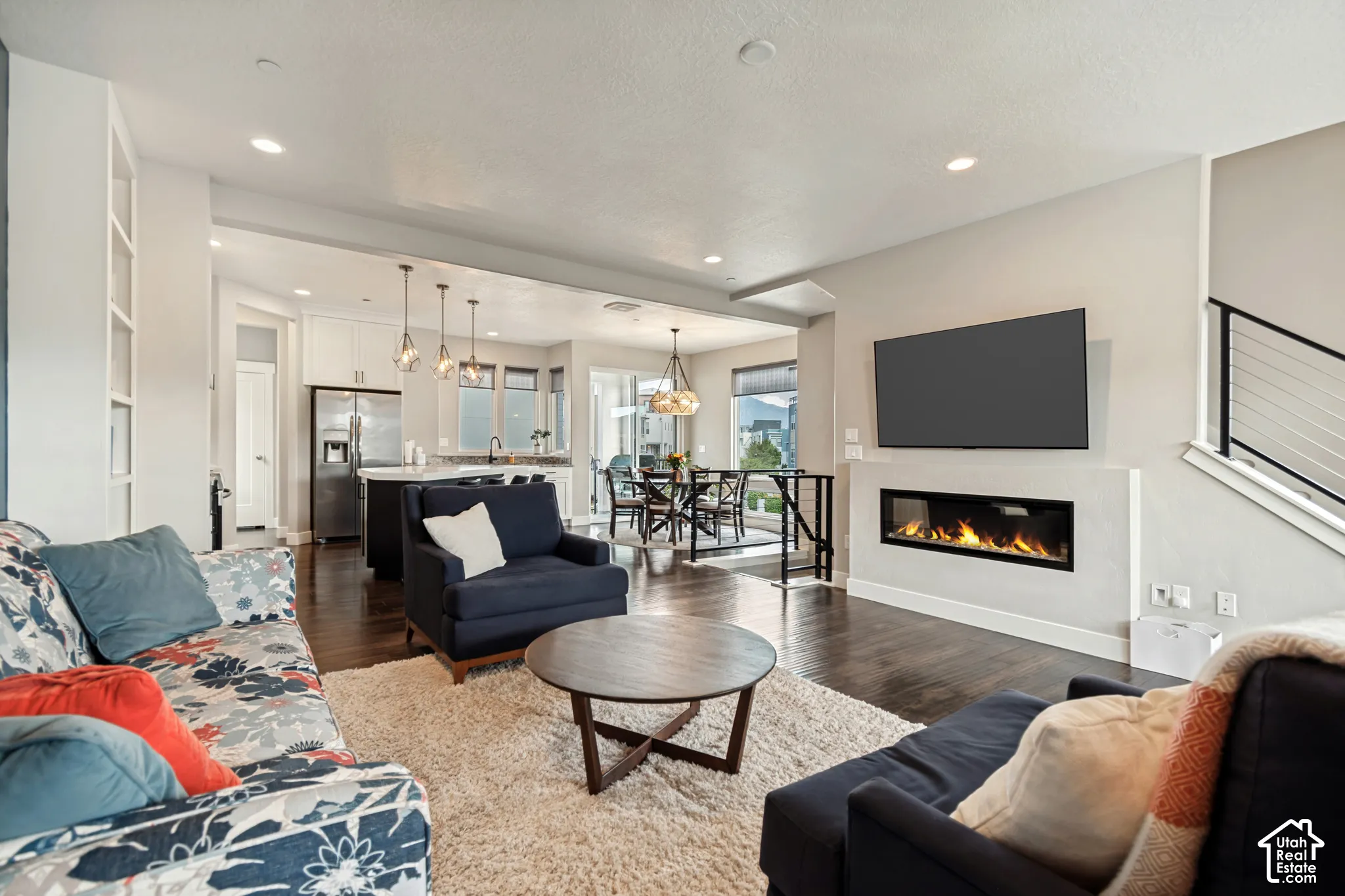 Open-concept living space featuring wood-finish flooring, a contemporary linear fireplace, and built-in shelving