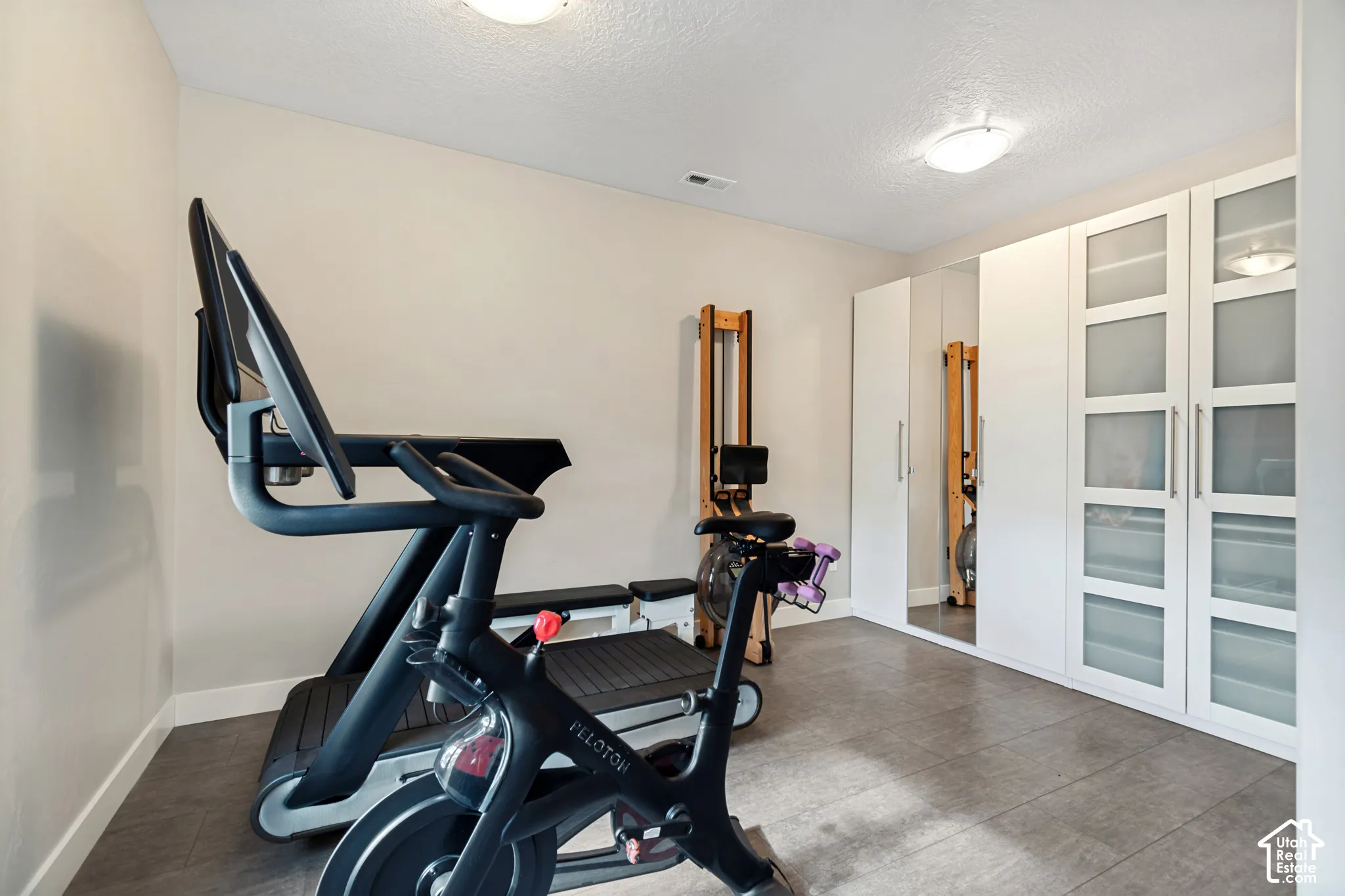 Recessed lighting, built-in cabinetry with frosted glass panels, full-length mirrored panel, and light-toned flooring