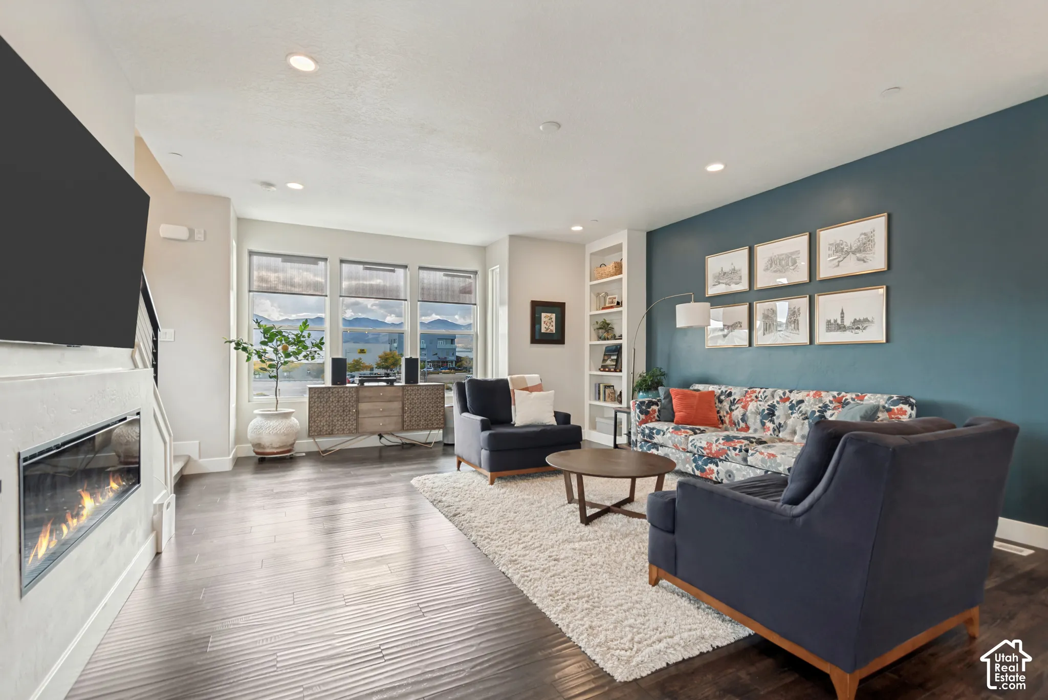 Wood-finish flooring, recessed lighting, built-in shelving, and a modern fireplace