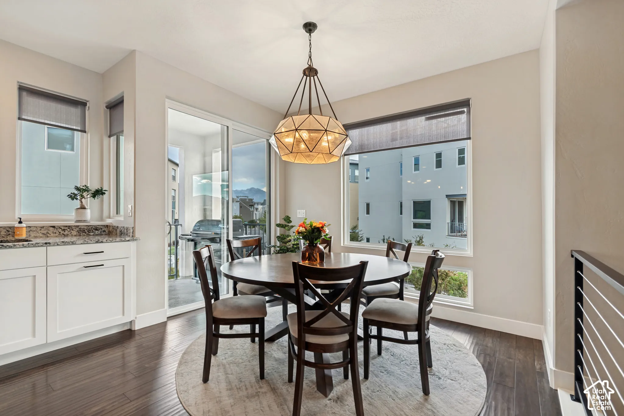 Wood-finish flooring, white cabinetry with dark hardware, stone countertop, large window, and glass sliding door
