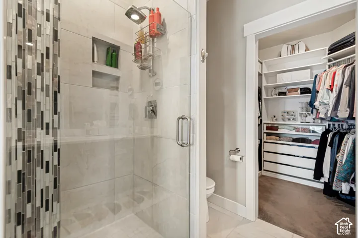 Glass-enclosed shower with subway tile, mosaic accent wall, and built-in shelving