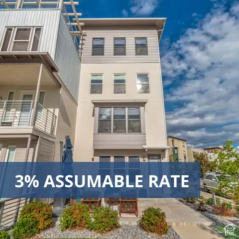 Three-story contemporary townhouse exterior featuring a combination of stucco and horizontal siding, a private concrete patio, and an upper-level balcony with metal railings