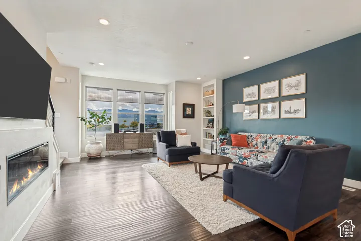 Wood-finish flooring, recessed lighting, built-in shelving, and a modern fireplace