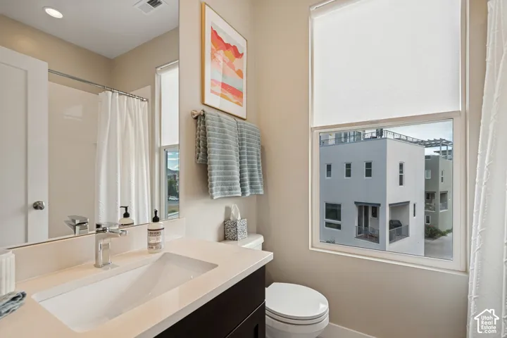 Bathroom featuring a single vanity with an integrated sink, polished chrome faucet, and a large mirror