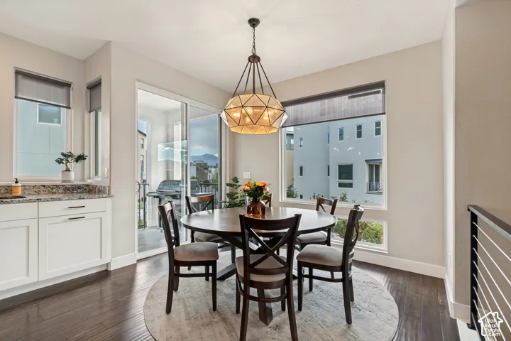 Wood-finish flooring, white cabinetry with dark hardware, stone countertop, large window, and glass sliding door