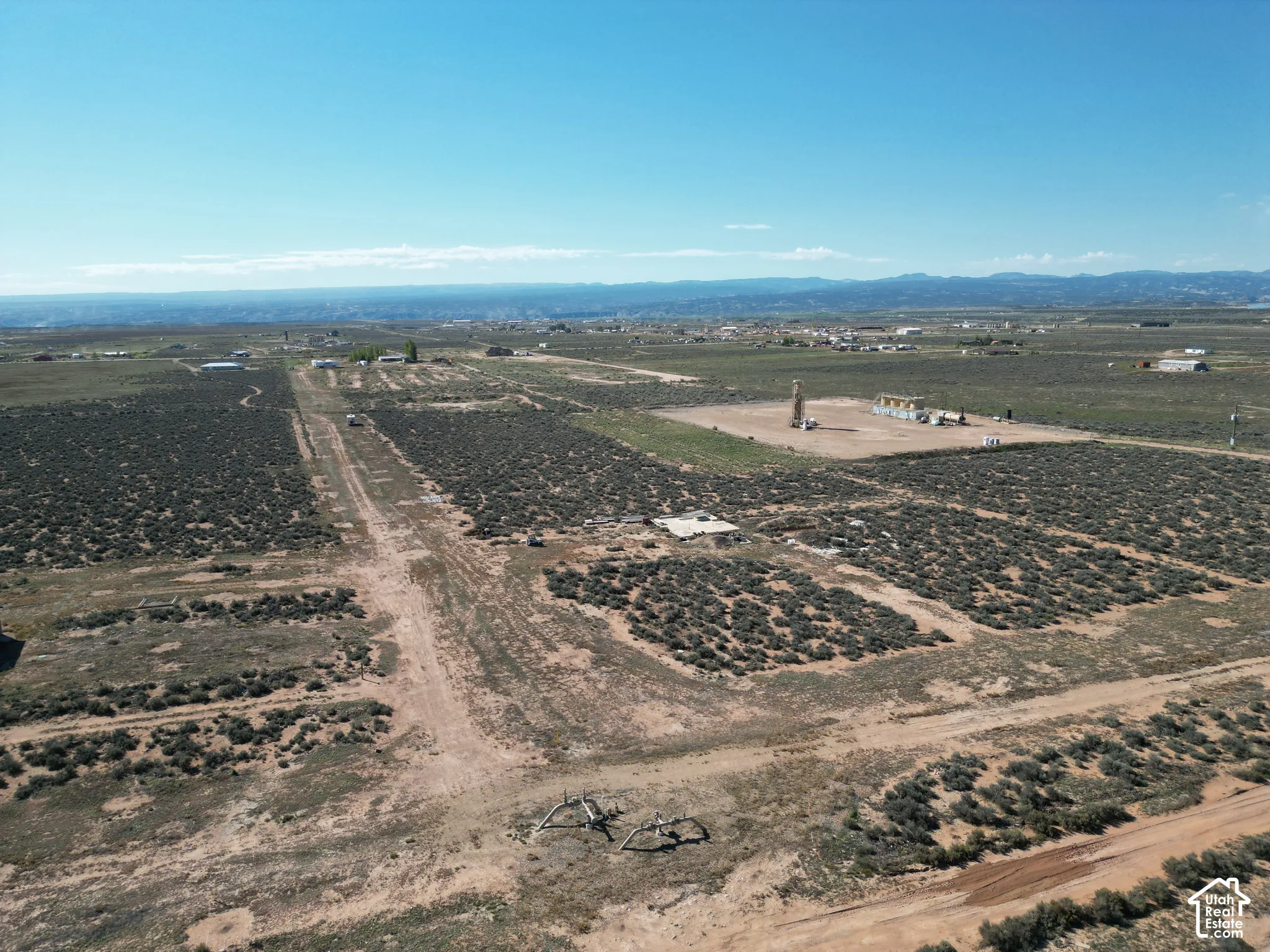 Expansive desert acreage featuring native vegetation, dirt access roads, and mountain terrain in the distance