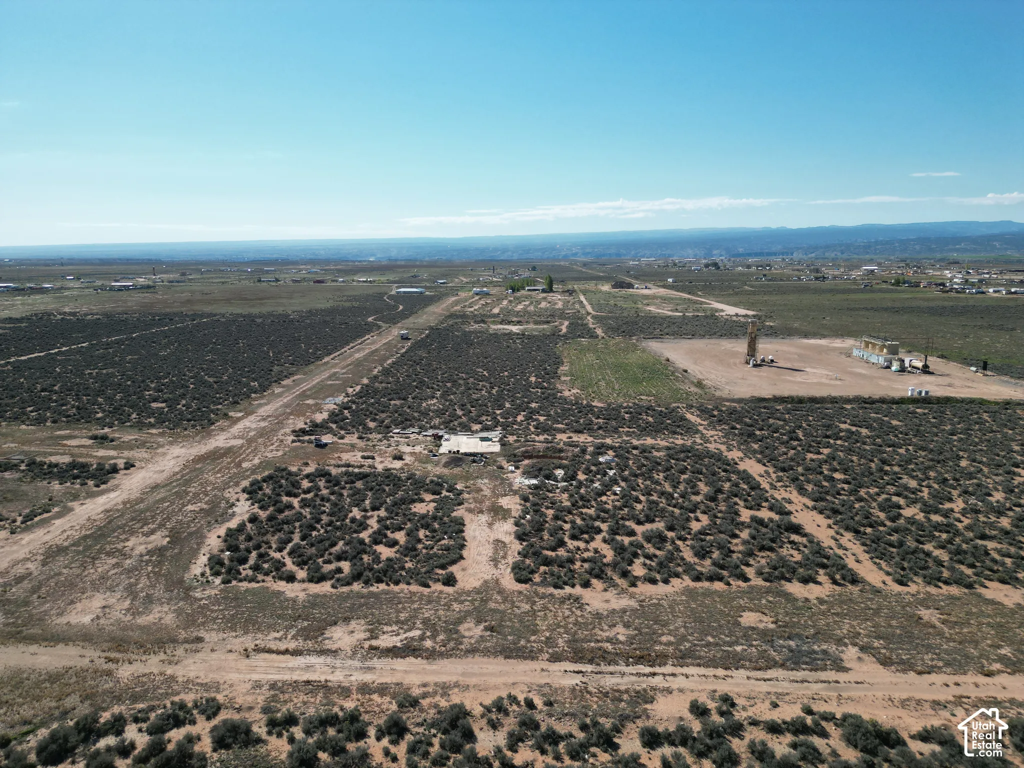 Expansive acreage featuring native desert vegetation, dirt access paths, and mountain horizons