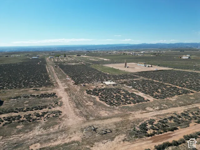 Expansive desert acreage featuring native vegetation, dirt access roads, and mountain terrain in the distance