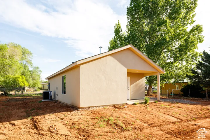 Stucco exterior featuring a covered porch, gabled roofline, and mature trees