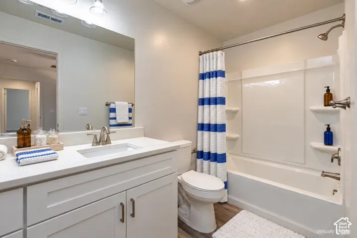 Primary Bedroom EnSuite Bathroom featuring a vanity with a white countertop and rectangular undermount sink, a large wall-mounted mirror, brushed metal fixtures, and a shower-tub combination with integrated shelving