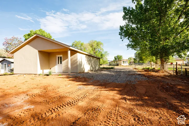 Exterior featuring a stucco facade, covered porch, and gravel driveway