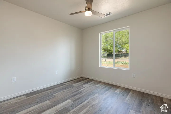 2nd Bedroom featuring neutral wall paint, wood-finish flooring, a sliding glass window, and an integrated ceiling fan with light fixture
