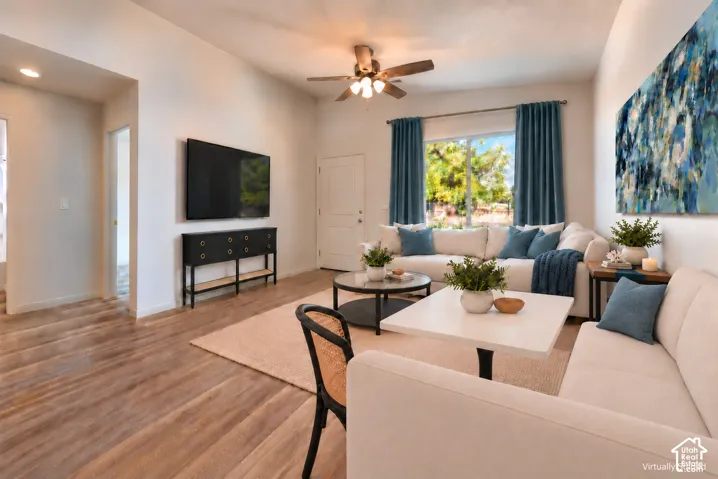Living area featuring high ceilings, wood-finish flooring, and a ceiling fan with integrated lighting