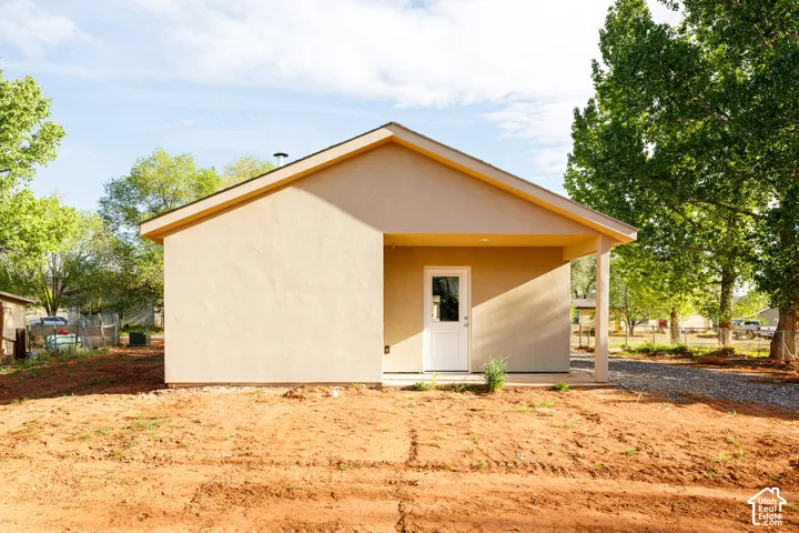 Stucco exterior featuring a gabled roofline, recessed covered porch, and single-light entry door