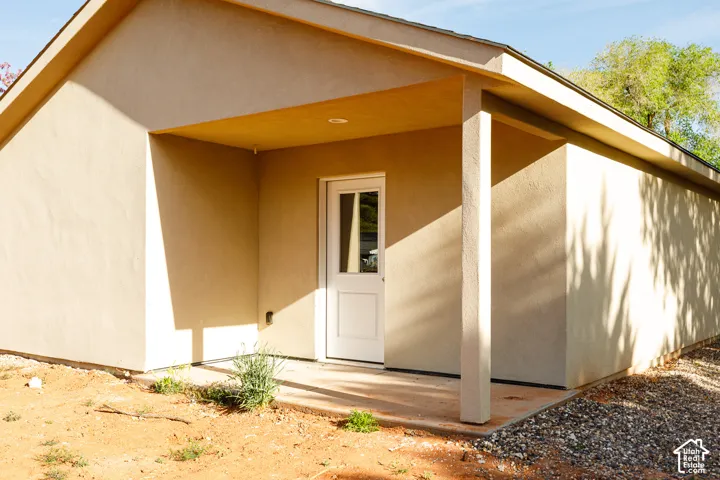 Stucco exterior featuring a covered patio, recessed ceiling lighting, and a paneled entry door with a glass insert