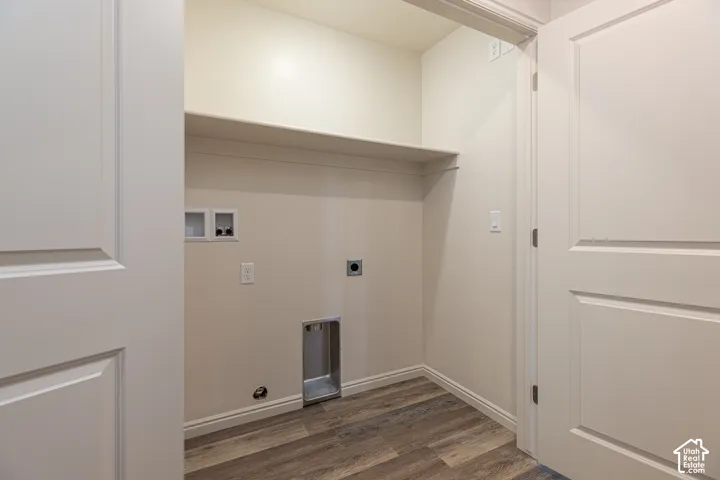 Utility area featuring wood-finish flooring, a built-in overhead shelf, and recessed laundry hookups