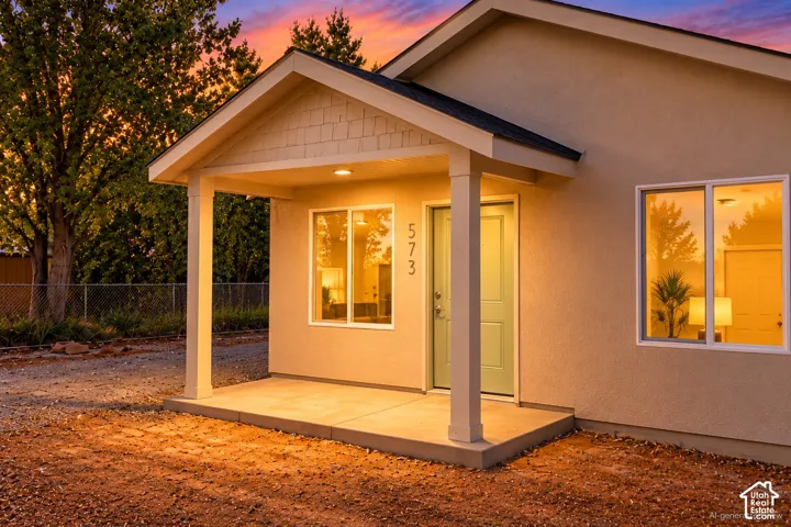 Exterior featuring a covered porch, stucco siding, shake shingle gable detailing, and dual-pane windows