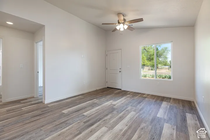 Interior space featuring vaulted ceilings, wood-finish flooring, a ceiling fan with integrated light fixture, and natural lighting provided by a single-pane window