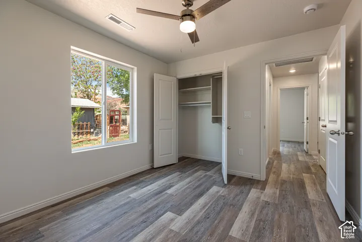 Primary Bedroom featuring wood-finish flooring, a ceiling fan with integrated lighting, and a reach-in closet with built-in shelving
