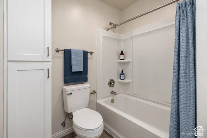 Full-height white built-in cabinetry, white bathtub and shower surround with integrated shelving, and metal hardware fixtures