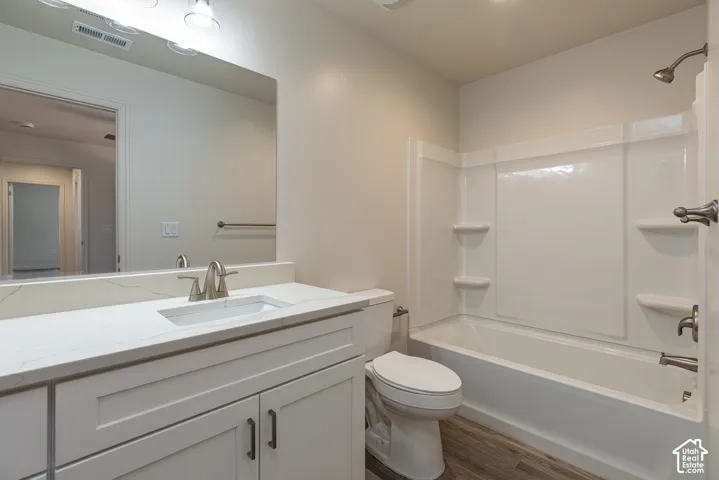 Primary Bedroom En Suite Bathroom featuring a white vanity with a light-toned stone countertop, integrated sink, undermount faucet, wall-spanning mirror, and a tub-shower combination with built-in shelving