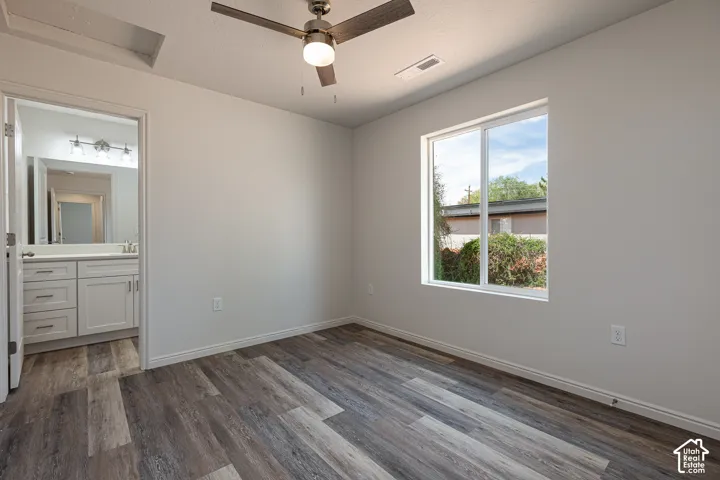 Primary Bedroom featuring wood-finish flooring, a ceiling fan with integrated lighting, and a window with exterior greenery