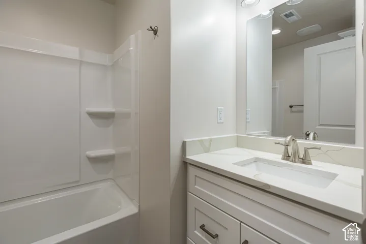 Bathroom featuring a white shaker-style vanity with stone-composite countertop, integrated rectangular sink, widespread brushed-nickel faucet, and a wall-to-wall vanity mirror