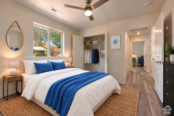 Primary bedroom featuring a ceiling fan, wood-finish flooring, and large windows with natural light