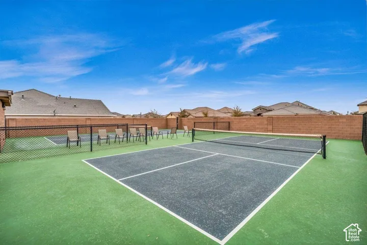 Private pickleball court featuring a multi-color hard surface, integrated net system, and black chain-link perimeter fencing enclosed by masonry walls