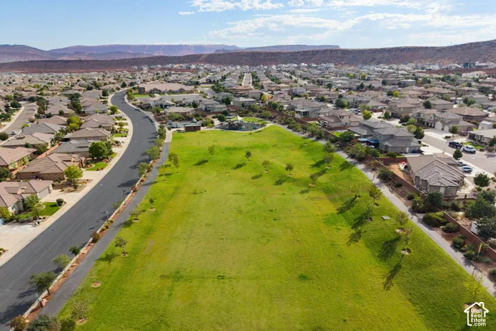 Expansive grass-covered lot featuring mature trees and a desert mountain backdrop