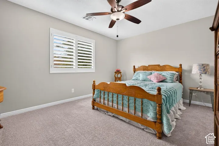 Neutral wall tones, installed plantation shutters, carpeting, and a multi-blade ceiling fan with integrated lighting