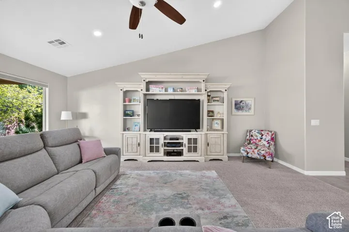 Vaulted ceilings featuring recessed lighting, a ceiling fan, and built-in floor-to-ceiling cabinetry with glass-paneled doors