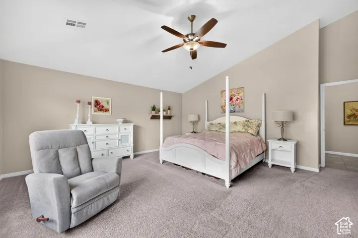 Vaulted ceiling featuring a central lighted ceiling fan, neutral wall tones, and carpeted flooring