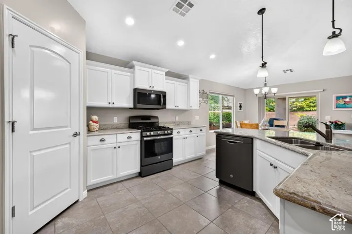 Kitchen featuring white shaker-style cabinetry, stone countertops, tile flooring, recessed lighting, and black appliances