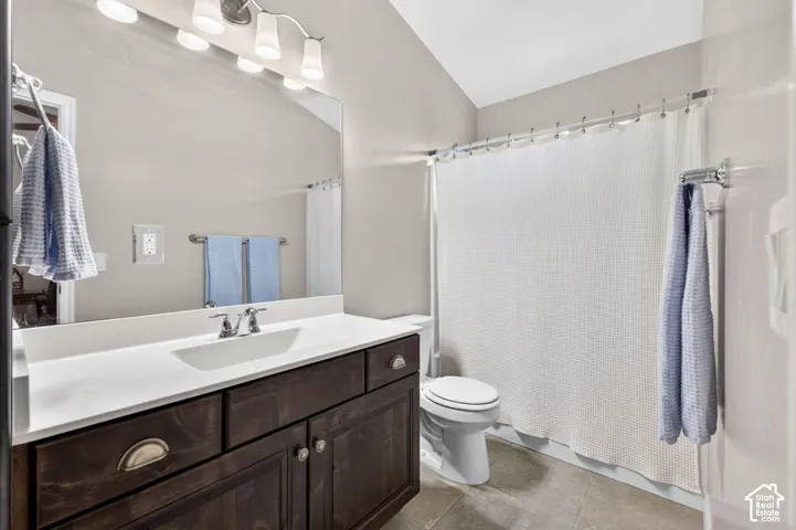 Bathroom featuring dark wood-finish cabinetry, a white countertop with an integrated sink, polished metal hardware, and large-format tile flooring