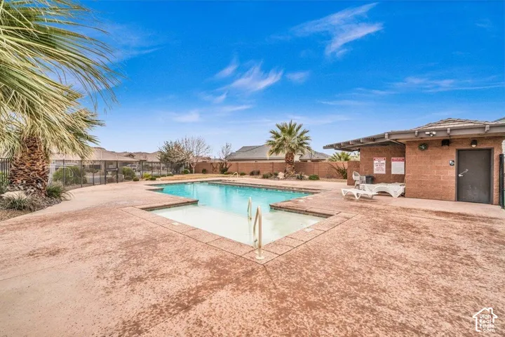 Swimming pool with tanning ledge, textured concrete decking, and concrete masonry pool house