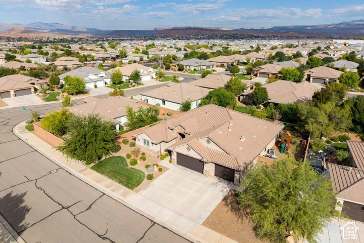 Single-story residence featuring a tile roof, an attached three-car garage, concrete driveway, and xeriscaped front yard with mountain backdrops