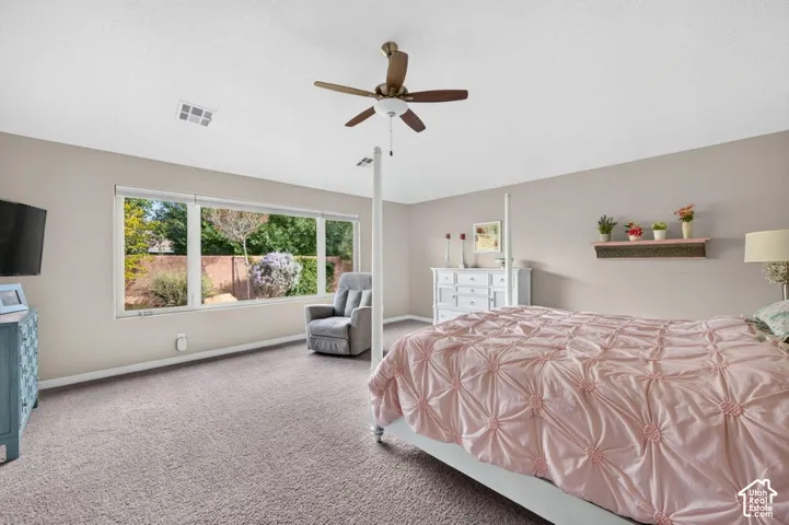 Neutral-toned interior space featuring a large picture window, wall-to-wall carpeting, and a ceiling fan with integrated lighting