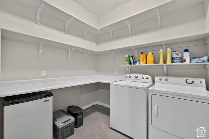 Laundry room featuring multi-level built-in shelving, stone-composite countertop, and tile flooring