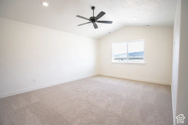 Primary bedroom with vaulted ceiling and ceiling fan.