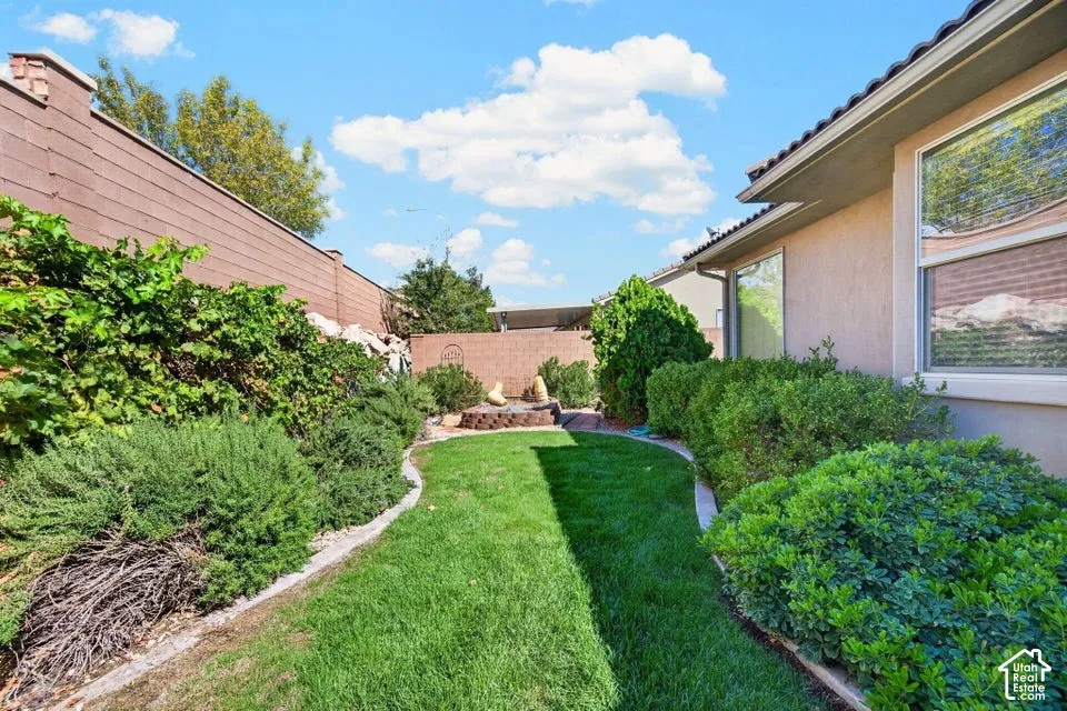 Private outdoor space featuring a landscaped lawn, concrete borders, perimeter masonry wall, and established greenery