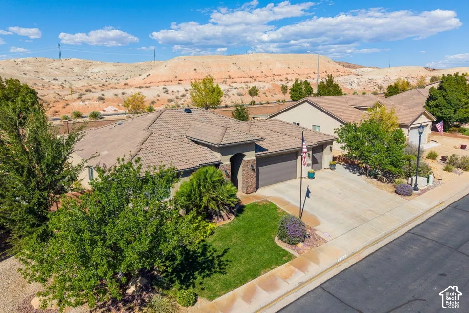 Modern single-story residence featuring a dark composite roof, three-car garage with dark exterior trim, and mature landscaping with established trees throughout the front grounds