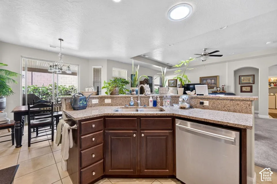 Kitchen featuring dark wood cabinetry, stone-finish countertops, dual-basin stainless steel sink with pull-down faucet, and stainless steel dishwasher
