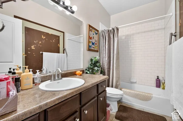 Bathroom vanity with a stone-finish countertop, oval drop-in sink, and wood-finish cabinetry featuring white subway tile tub surround